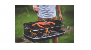 Mies grillaa makkaraa grillissä